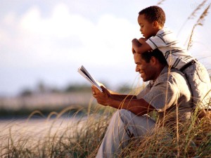 Pai e filho no campo lendo livro